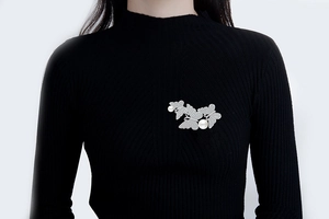 Detail of butterfly brooch with white pearls and zircons pinned on black knitwear