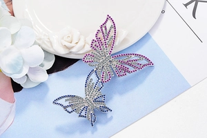 Details von silbernen Schmetterlingsbroschen mit lila und blauen Zirkonsteinen auf Weiß