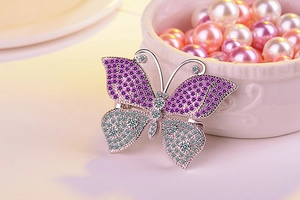 Detail shot of a silver butterfly brooch with purple and white zircon micro-inlay accents
