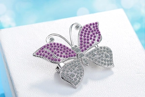 Detailed close-up of butterfly brooch with pink and white crystals on textured box