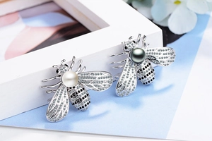 Detail shot of bee brooches with silver metal and sparkling zircon wings on a bright background