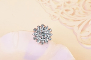 Close-up of sparkling sun-shaped brooch with marquise-cut cubic zirconia in rose gold