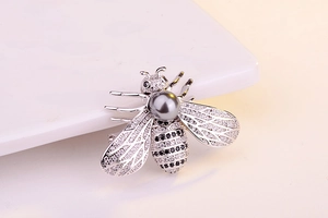 Macro shot of a bee brooch featuring black and white zircons and a large grey pearl