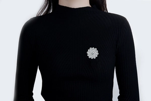 Close-up of sparkling zircon flower brooch pinned on a black knit sweater for women