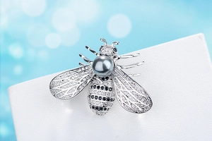 Macro shot of bee brooch featuring sparkling zircons and a central grey pearl detail