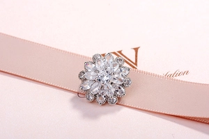 Detail of flower brooch featuring a round center stone and marquise-cut petals on pink ribbon