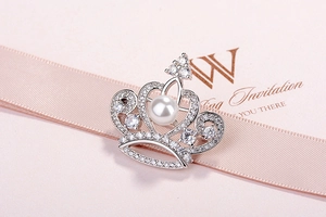 Close-up of silver crown brooch with a central pearl and zircon inlay on silk