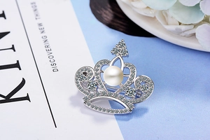 Detailed shot of a silver crown brooch with white pearl and sparkling zircon stones