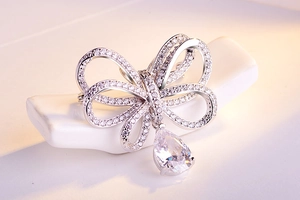 Détail macro d'une broche noeud en argent avec pavé de zircons et pendentif en poire