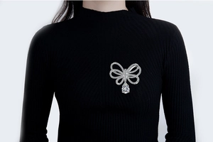 Détail macro d'une broche nœud en argent avec incrustation de zircon et goutte en poire