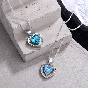 Collier cœur en zircon bleu avec chaîne argentée sur des marches en pierre