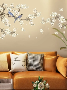 Detail view of magnolia flower wall decals with blue birds over a warm sofa backdrop