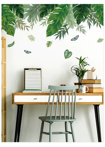 Détail de stickers muraux feuilles tropicales et monstera avec papillons bleus sur un mur