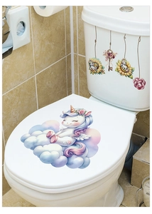 Vue détaillée des autocollants licorne rose et fleurs posés sur un abattant de WC en céramique