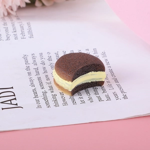 Detalle macro del dije de macaron de resina marrón con crema amarilla y mordida