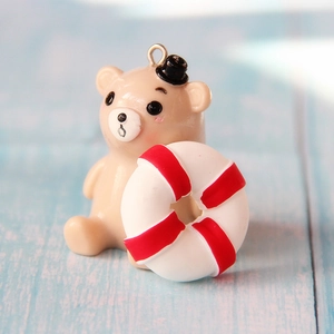 Macro view of khaki resin bear charm with a red lifebuoy and top metal hanging ring