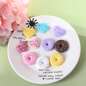 Colorful resin donut and heart cabochons in a ceramic tray for DIY phone case crafts