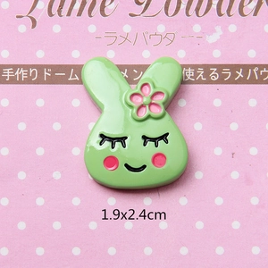Macro shot of a 1.9x2.4cm green resin rabbit charm with a pink flower for DIY crafts