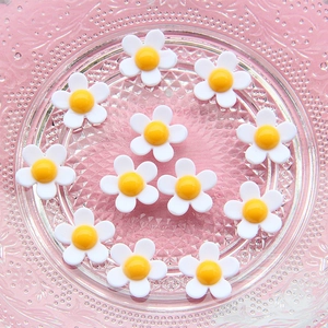 Macro view of white daisy charms with yellow centers for DIY crafts and phone cases