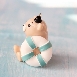 Detail shot of a cute brown bear resin pendant with a tiny top hat and lifebuoy ring