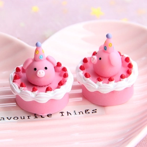 Macro shot of two miniature pink pig resin cakes with cream borders and strawberry details