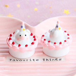 Pair of miniature resin pig cream cakes with rainbow hats on a pink ceramic tray