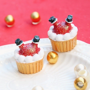 Dettaglio di figurine natalizie in resina con cupcake glitterati rossi e stivali di Babbo Natale