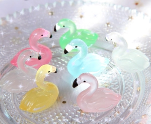 Leuchtende Flamingo-Anhänger aus Harz mit Glitzer auf Glastablett für DIY-Schmuck