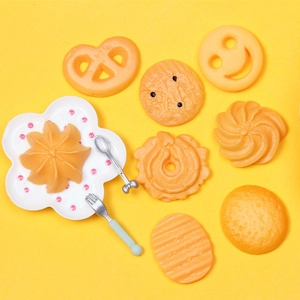 Flat lay of resin food play miniatures with heart cookies and smiley biscuits on yellow background
