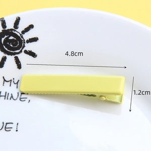 4.8cm cream yellow rectangle duckbill hair clip with polished finish on a ceramic plate