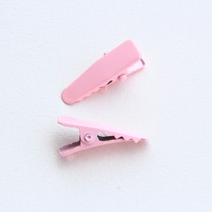 Dettaglio di fermagli per capelli a becco d'anatra in metallo rosa opaco con molla interna