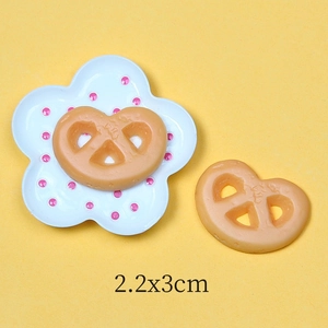 Detailed macro view of resin pretzel miniature charms with 2.2x3cm size markers