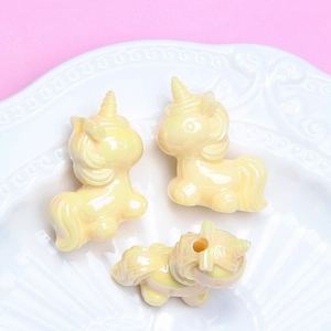 Détail de perles licorne nacrées pour bracelets DIY sur un fond de couleur rose