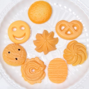 Flat lay of realistic resin miniature cookies and pretzels on a white ceramic plate