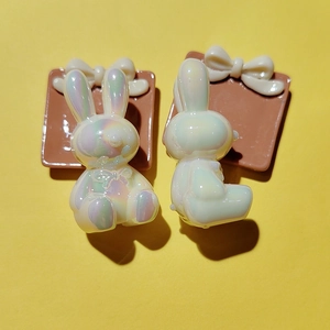 Detailed macro view of pearlescent rabbit charms with white bows for DIY jewelry