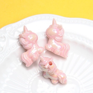 Détails de perles de licorne en acrylique nacré pour bijoux DIY sur une assiette blanche