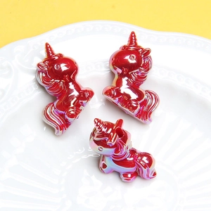 Vue détaillée de trois perles licornes en acrylique rouge iridescent dans un plat