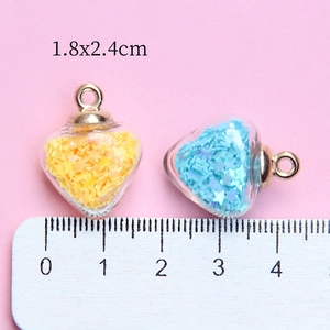 Heart shaped glass pendants with star sequins and golden rings on pink background