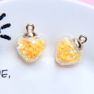 Detail view of heart-shaped glass pendants filled with yellow star sequins and silver rings