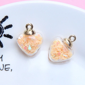 Close-up of heart-shaped glass pendants filled with peach star sequins and gold hardware