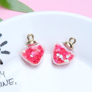 Close-up of heart-shaped glass charms with red star sequins and gold metal rings