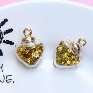 Detail view of heart-shaped glass pendants filled with golden star sequins and metal caps