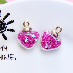 Close-up of heart-shaped glass pendants filled with rose red star sequins and gold ring