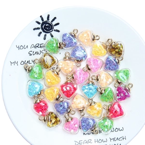 Colorful heart-shaped glass pendants filled with glitter stars on a white plate