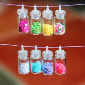 Dettaglio di mini bottiglie dei desideri in vetro con paillettes per gioielli DIY