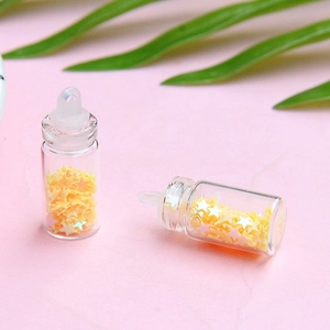 Dettaglio di mini bottiglie di vetro con paillettes a stella gialla e tappi per gioielli fai-da-te