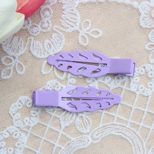 Elegant set of two purple leaf-shaped alloy hair clips on vintage lace fabric backdrop