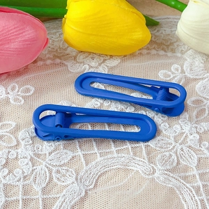 Detail of matte blue U-shaped non-marking duckbill hair clips on white lace background