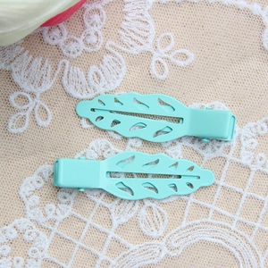 Detail of two mint green leaf hair clips with hollow design on lace background