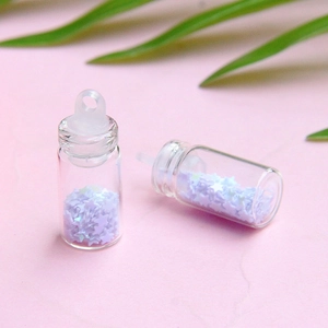 Macro di mini bottiglie dei desideri con paillettes a stella viola su sfondo rosa